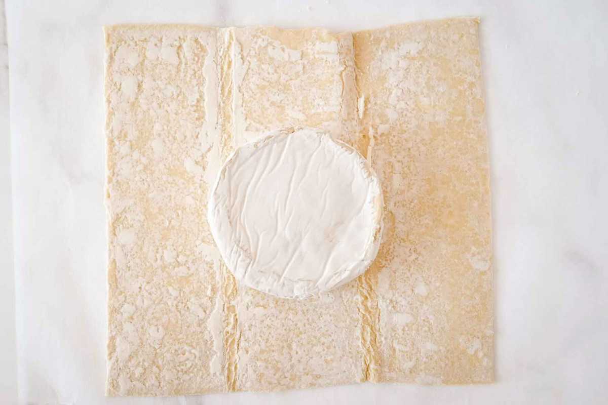 brie wheel with outer rind on a sheet of puff pastry.