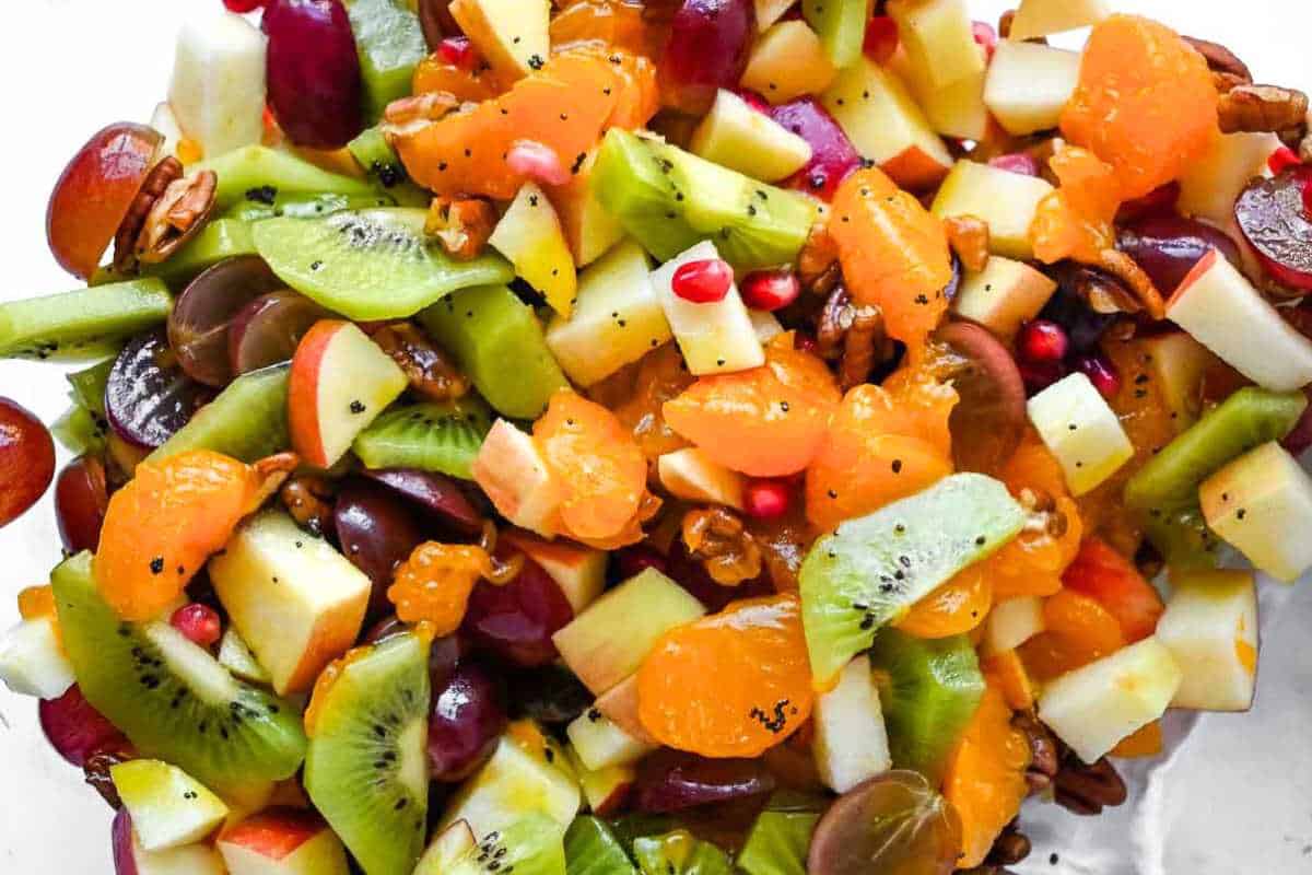 thanksgiving fruit salad ingredients in a bowl topped with lime vinaigrette.