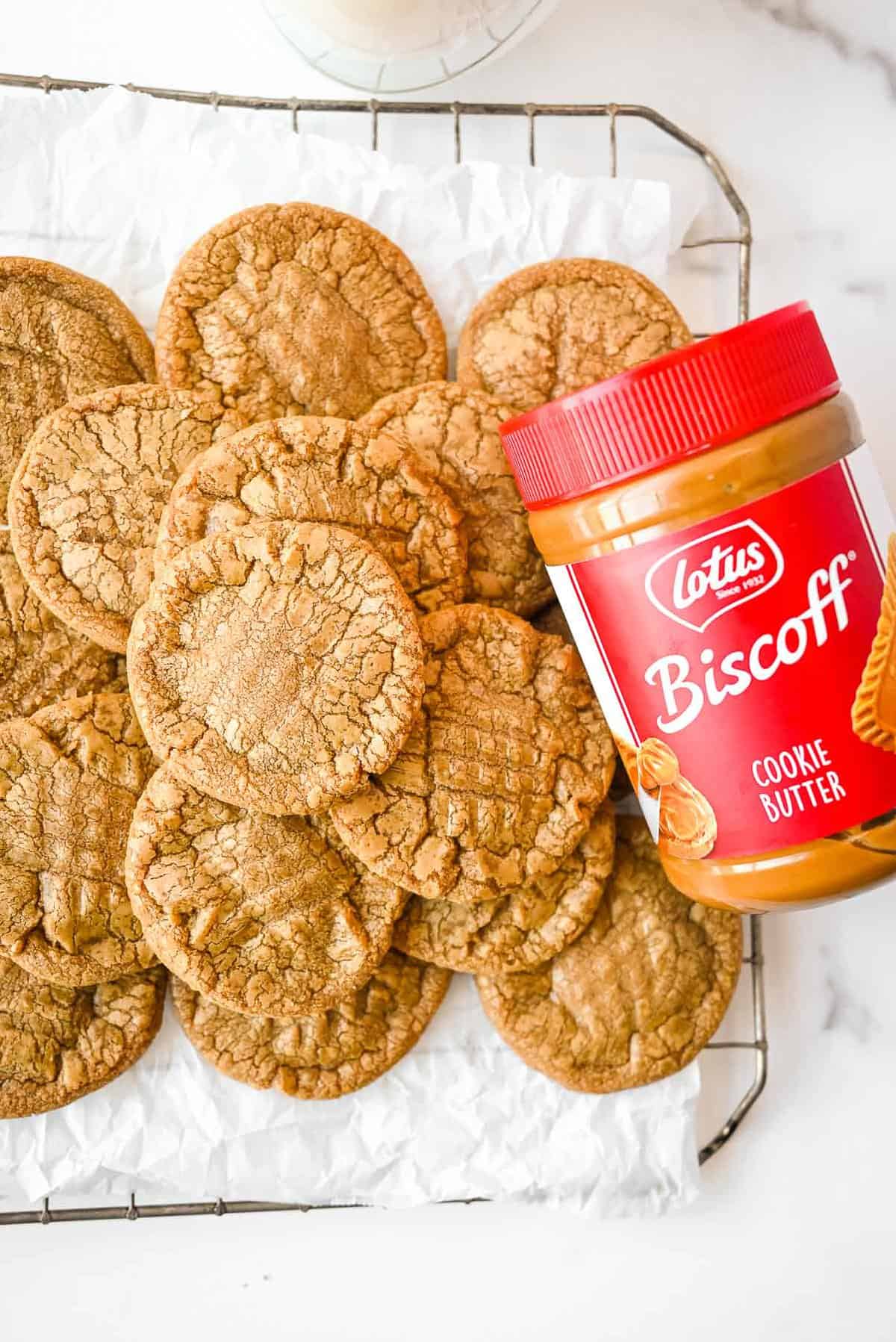 pile of cookie butter cookies on a cooling rack with a jar of biscoff.