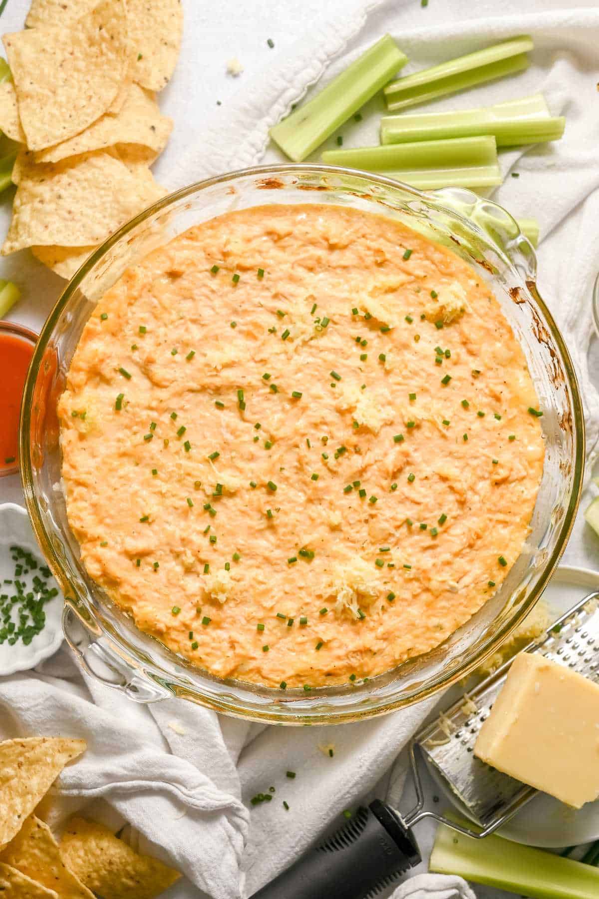 flat lay photo of buffalo chicken dip with ingredients around the pie plate.
