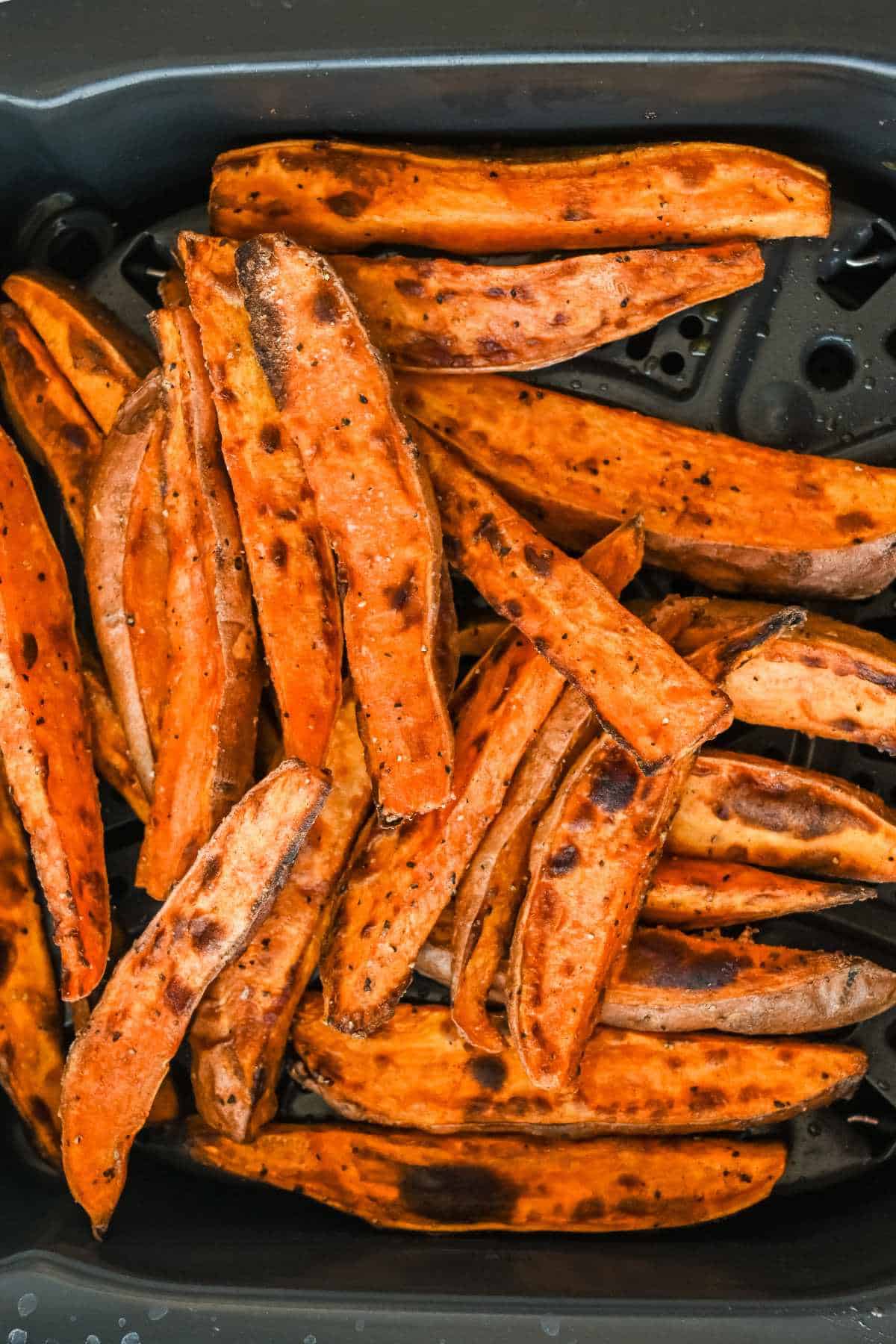 cooked air fryer sweet potato wedges close up in air fryer basket.