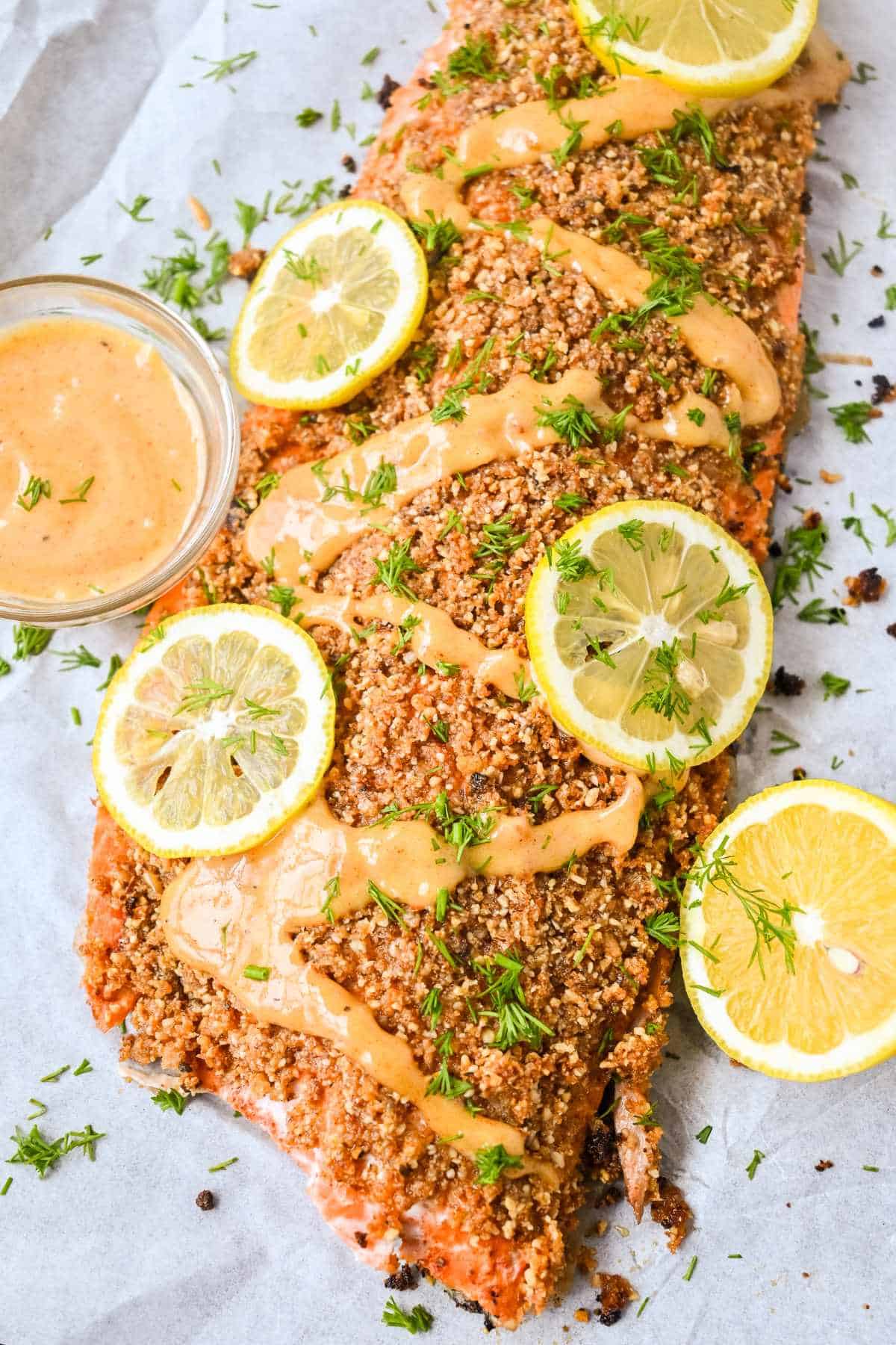 full fillet of salmon with almond crust topped with lemons sauce and dill.