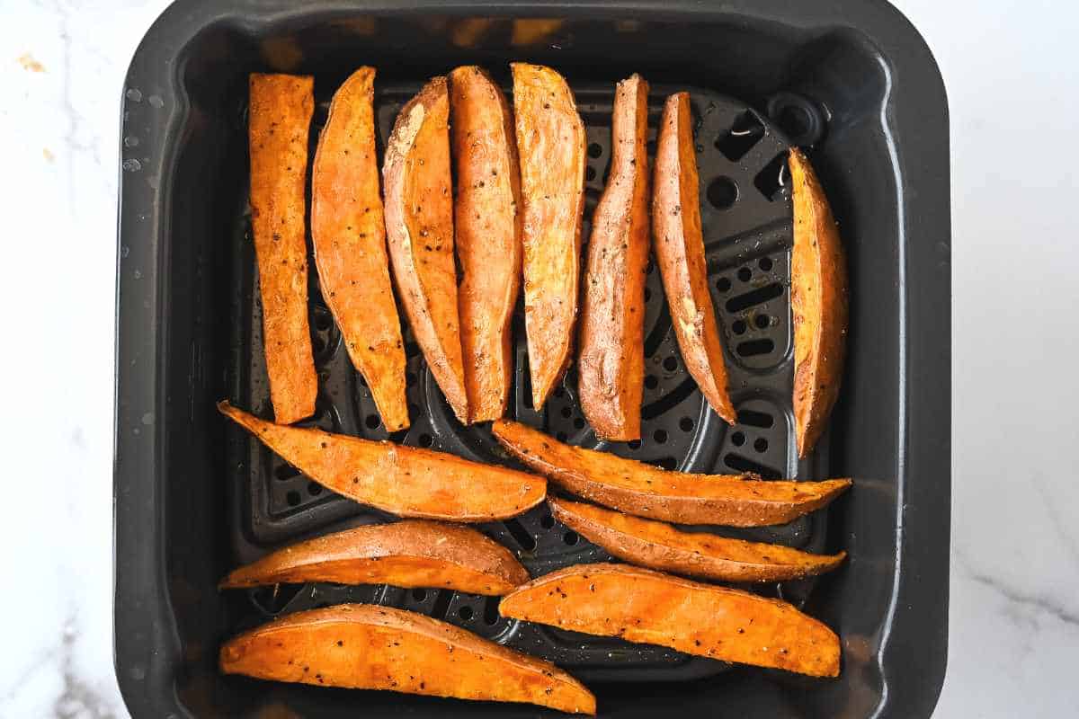 cooked sweet potatoes in an air fryer basket.