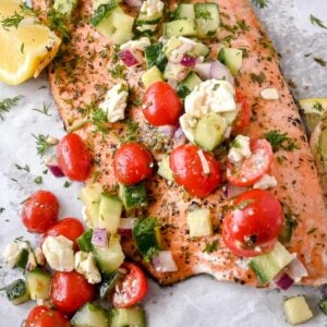 close up shot of greek salmon with cucumber tomato salad topping.