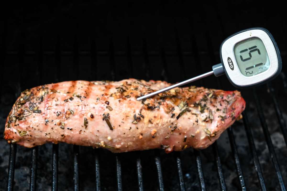finished pork on the grill with a meat thermometer.