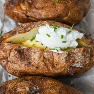 featured image showing close up of baked potato topped with sour cream, butter, and chives.