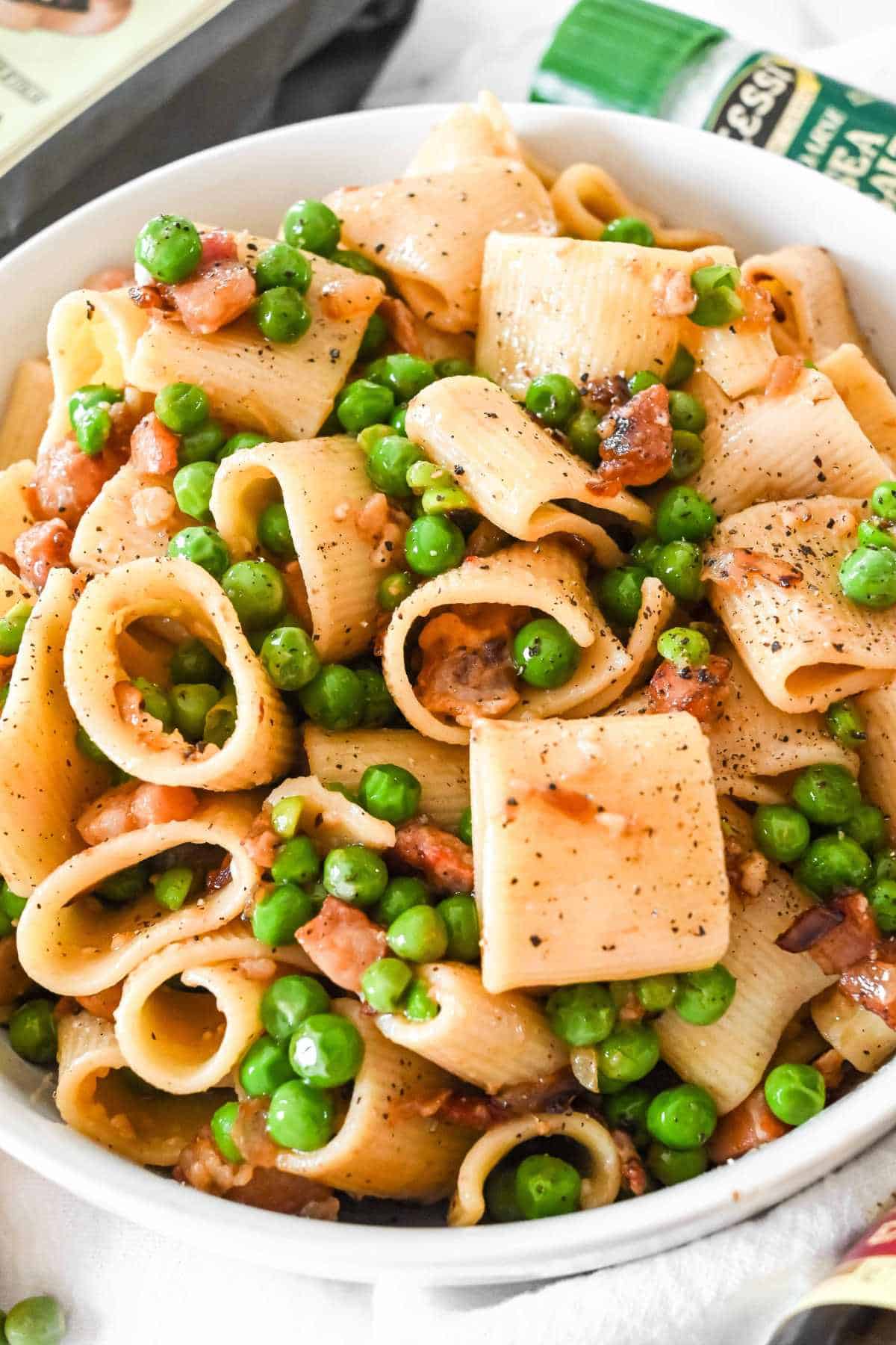 pasta with peas and pancetta in a white bowl.