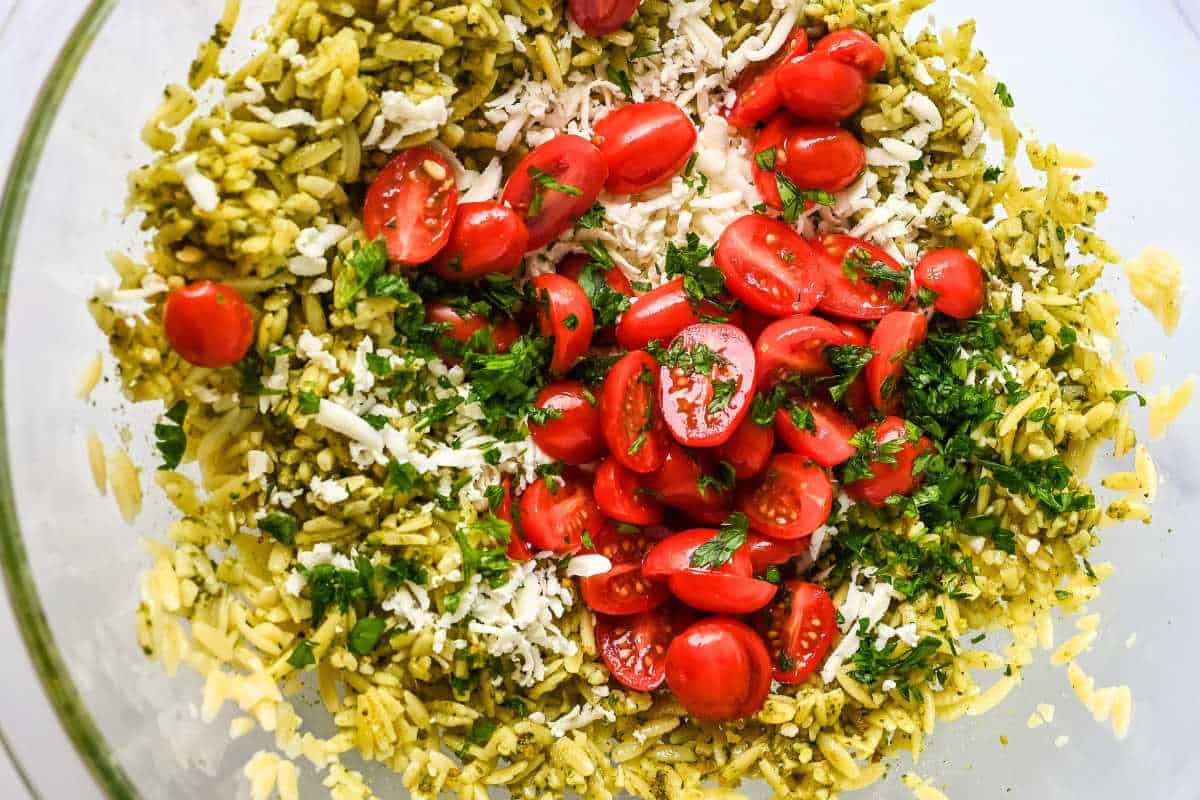 pesto orzo salad ingredients in a glass bowl.