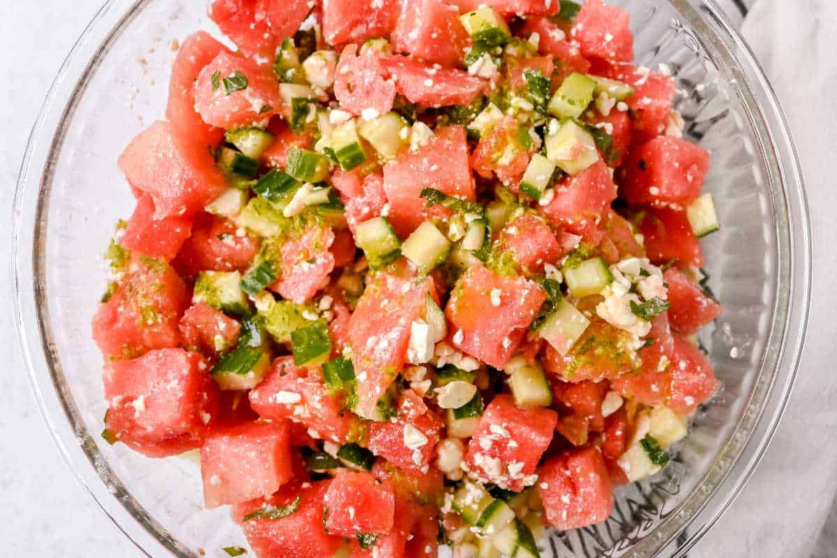 watermelon basil salad with dressing in a glass bowl.