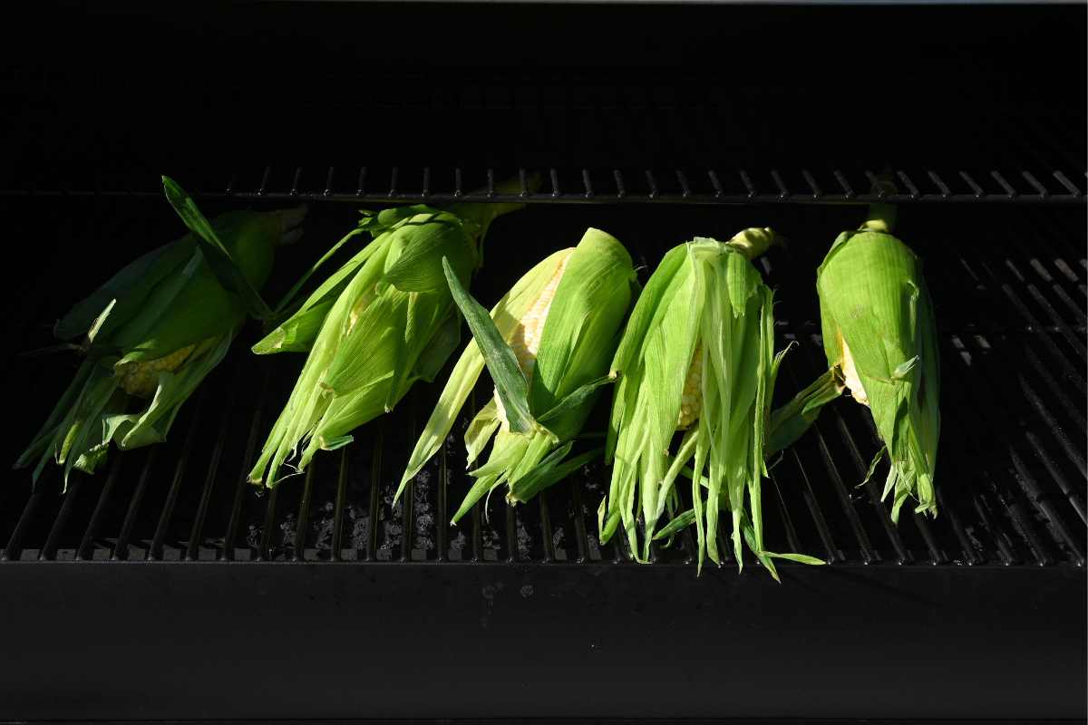 corn in the husks on a grill.