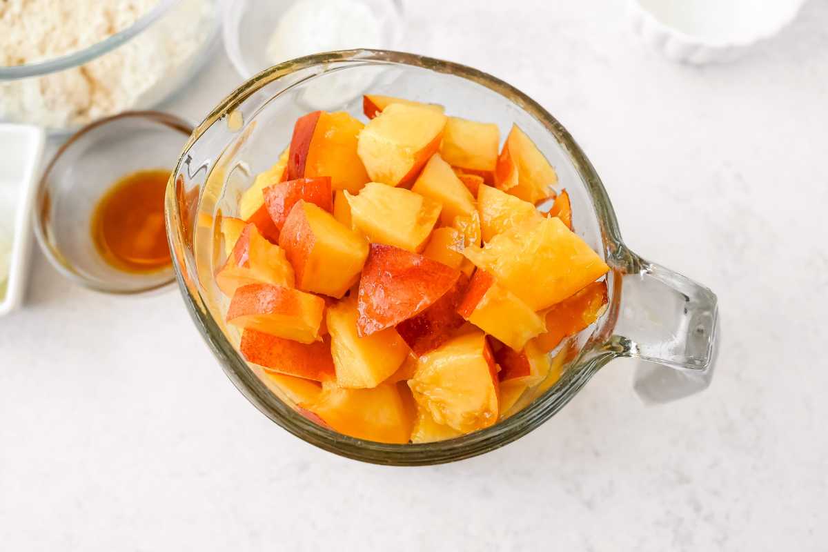 diced nectarines in a glass cup on a light gray background.