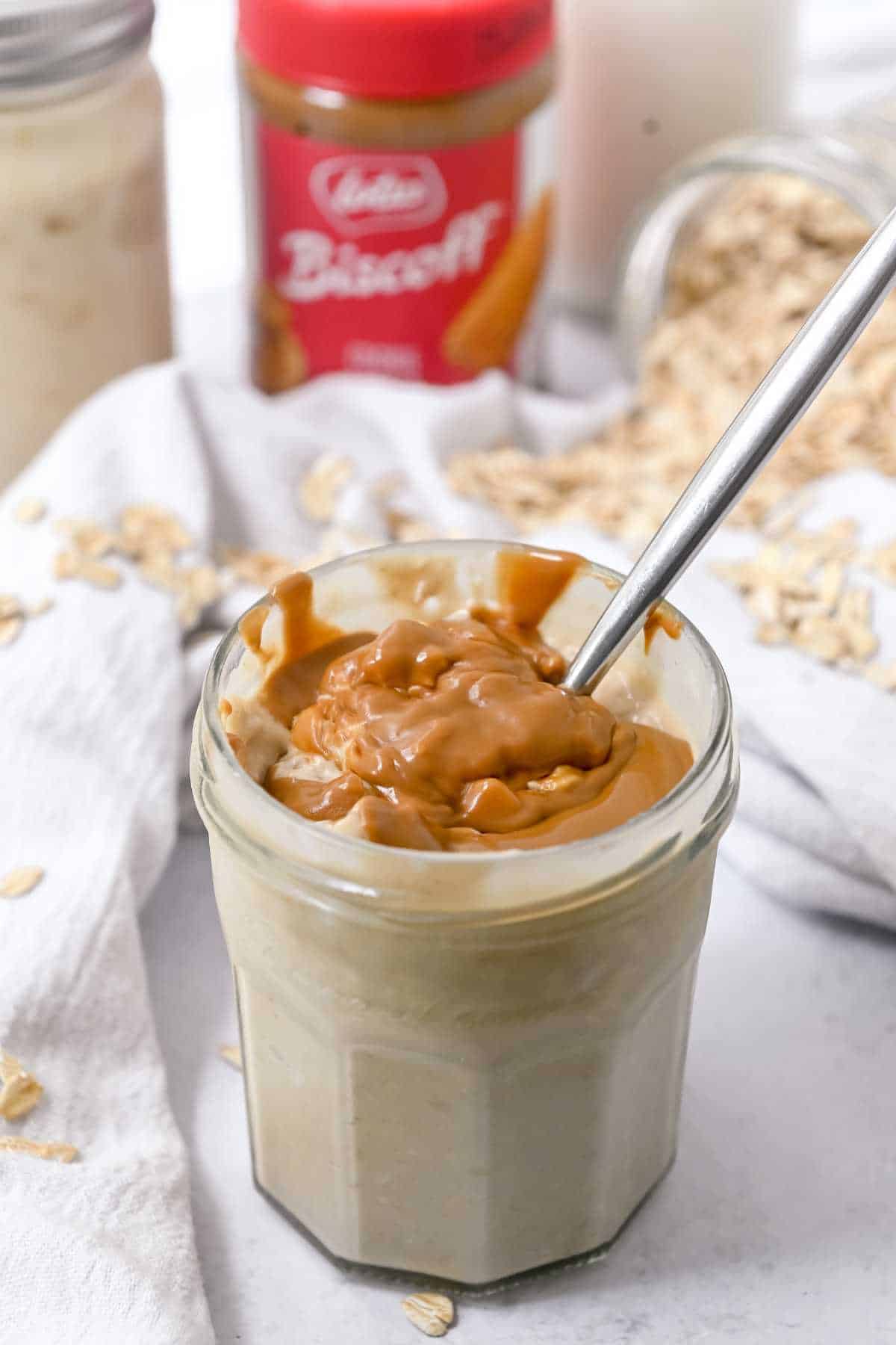 jar of biscoff overnight oats on a white background with Biscoff and oats behind.
