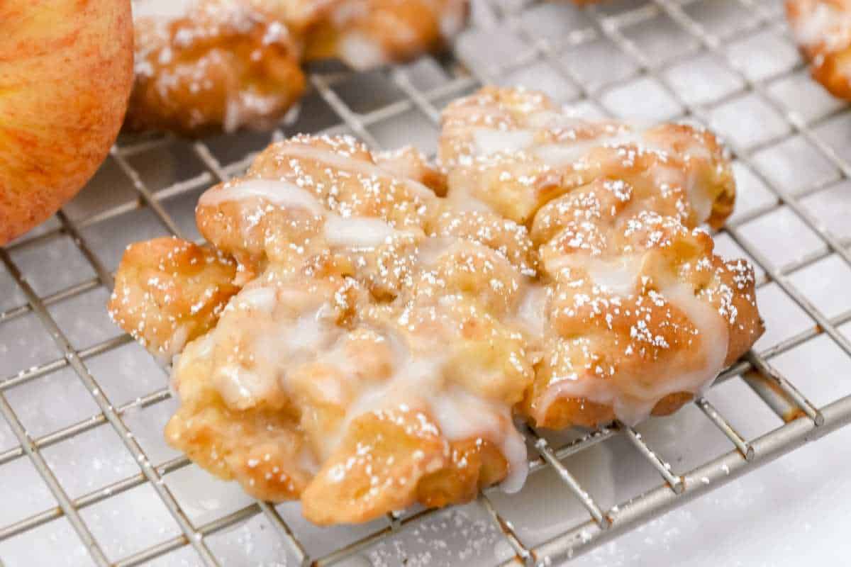 close up shot of glazed apple fritter on a wire rack.