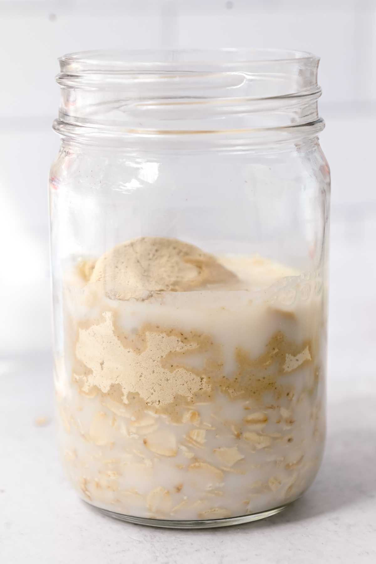 oatmeal, protein powder, and almond milk in a glass jar.