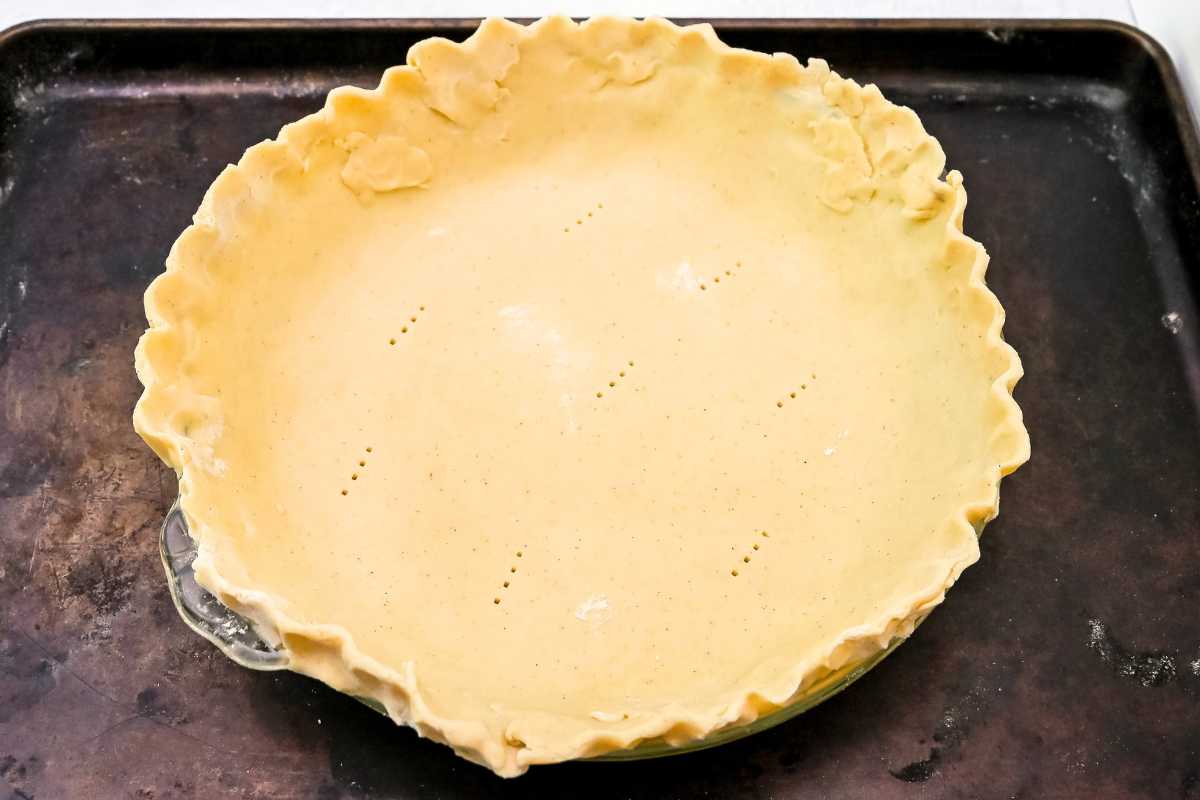 unbaked pie crust in a pie plate on a sheet pan.