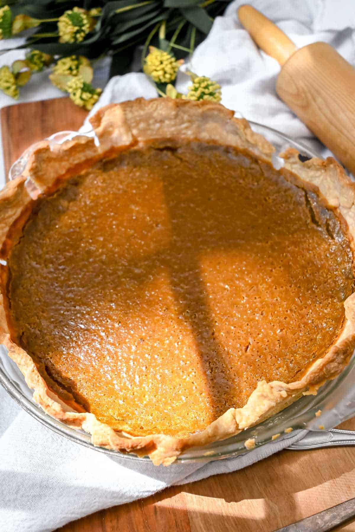 full view of eggless pumpkin pie on a white towel on a wooden board.