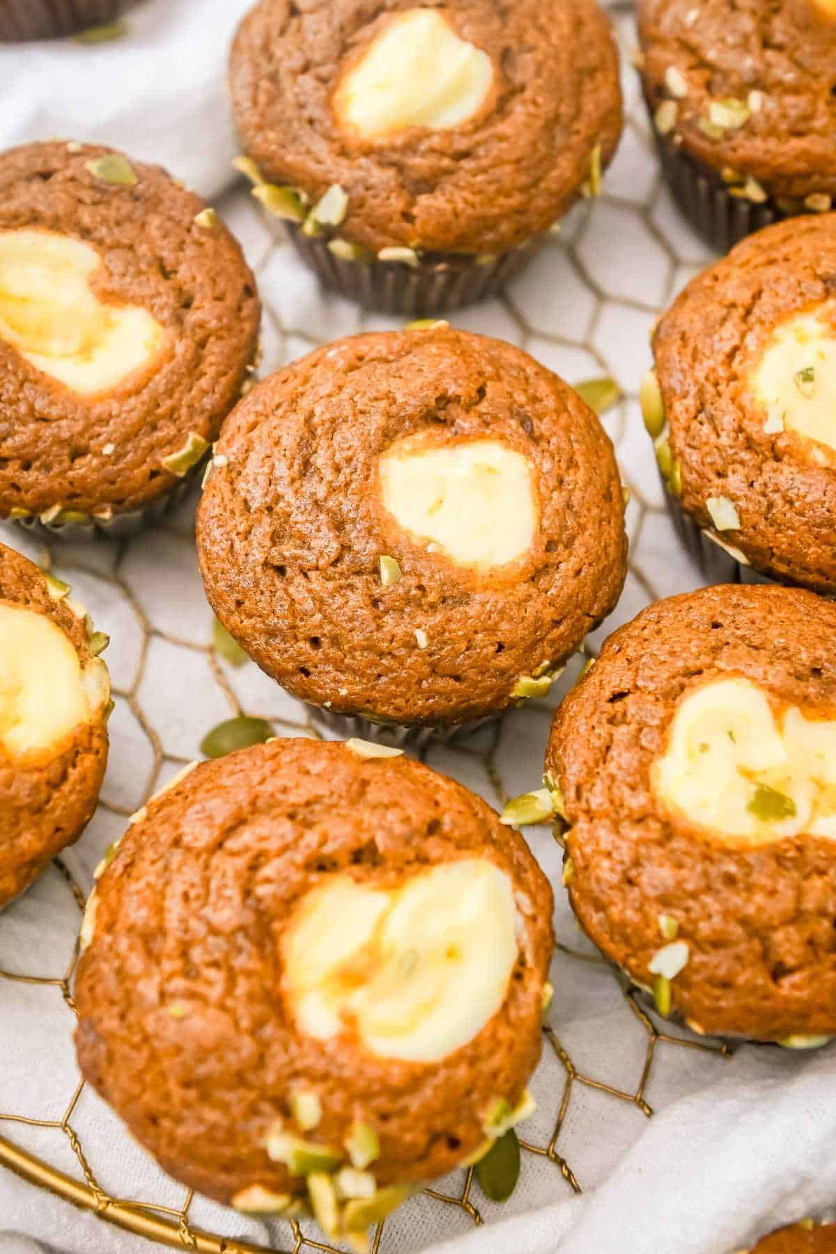 starbucks pumpkin muffins topped with cream cheese filling on a gold wire plate.