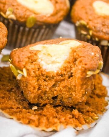 featured image of starbucks pumpkin muffins with a bite take out and topped with cream cheese filling.