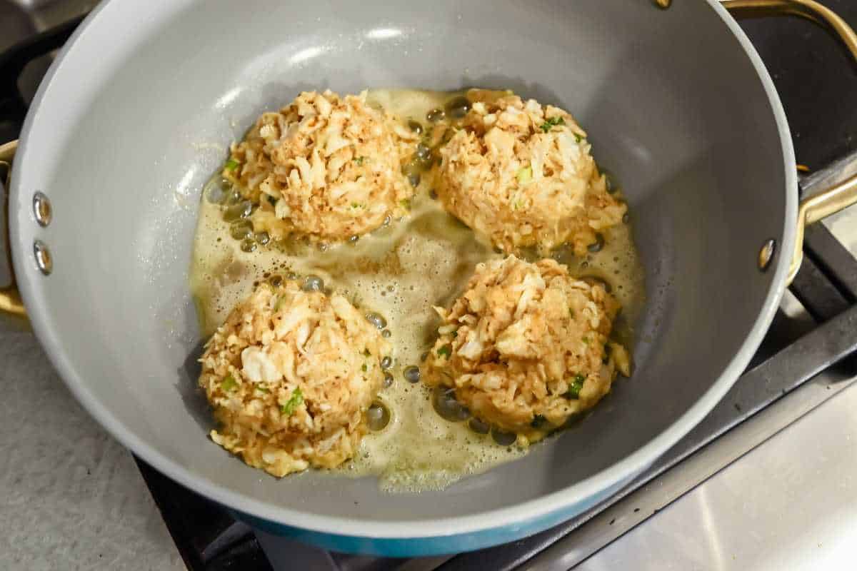 crab cakes in a frying pan in butter.