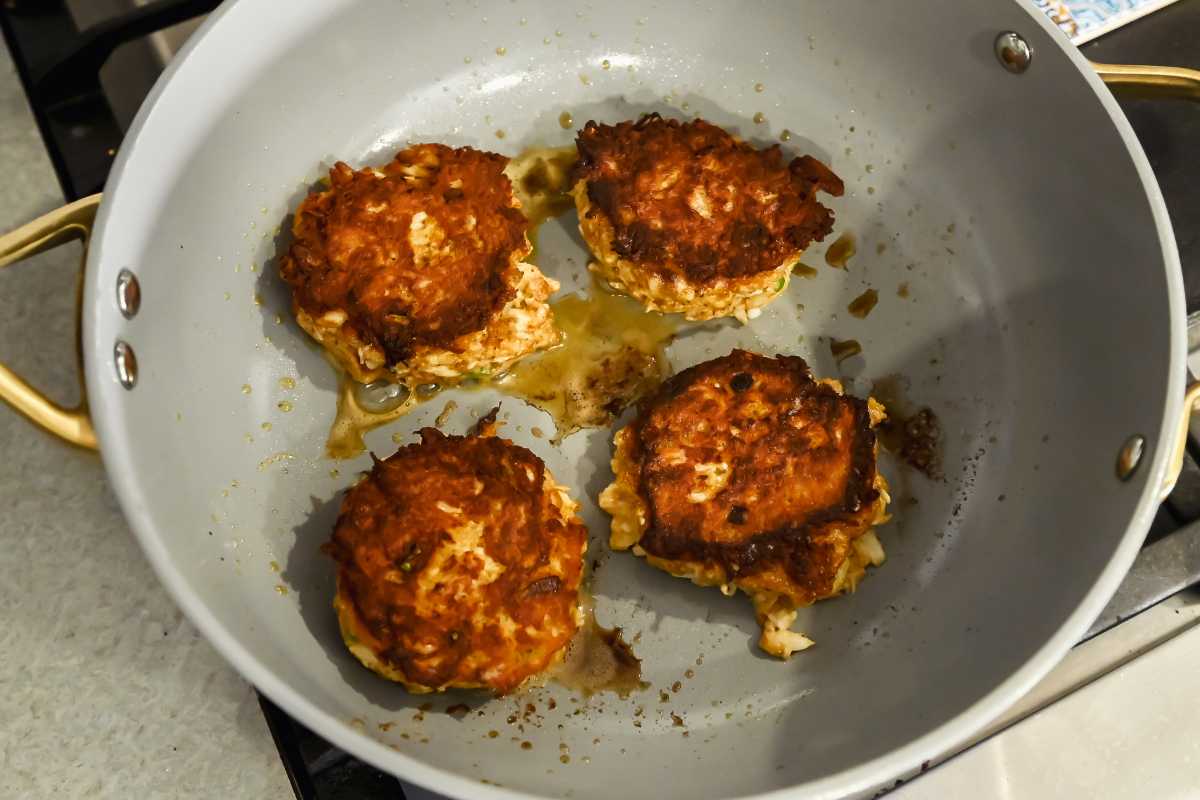 flipped over crab cakes in a pan.