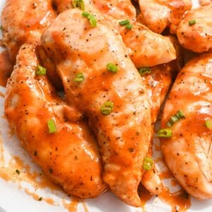 homemade frank's buffalo wing sauce on chicken tenders topped with green onions.