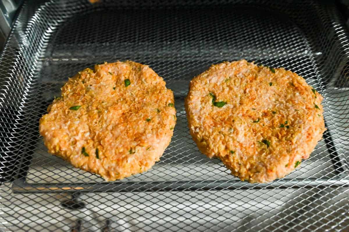 cooked chicken burgers on an airy fryer tray.