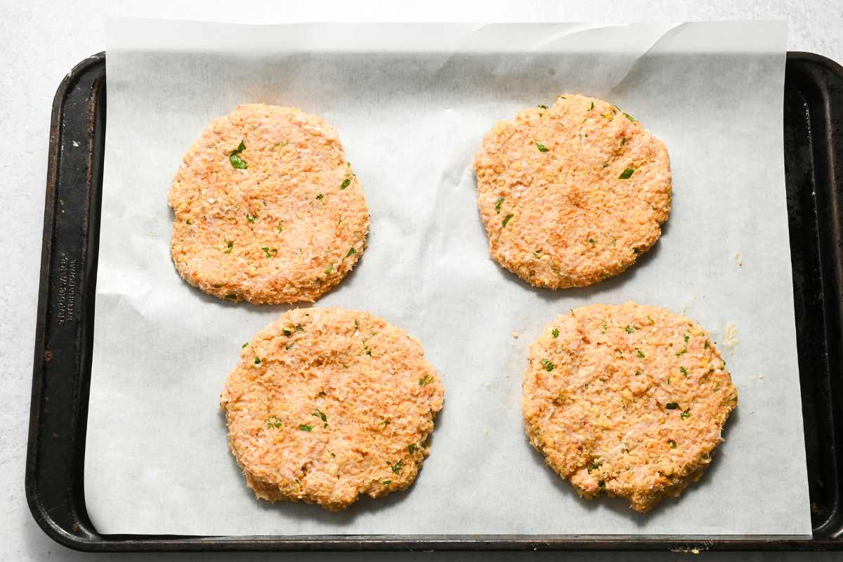 uncooked chicken burgers on a sheet pan.