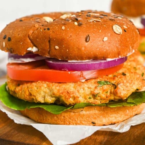 close up of air fryer chicken burgers on a bun with onion, lettuce, and tomato.