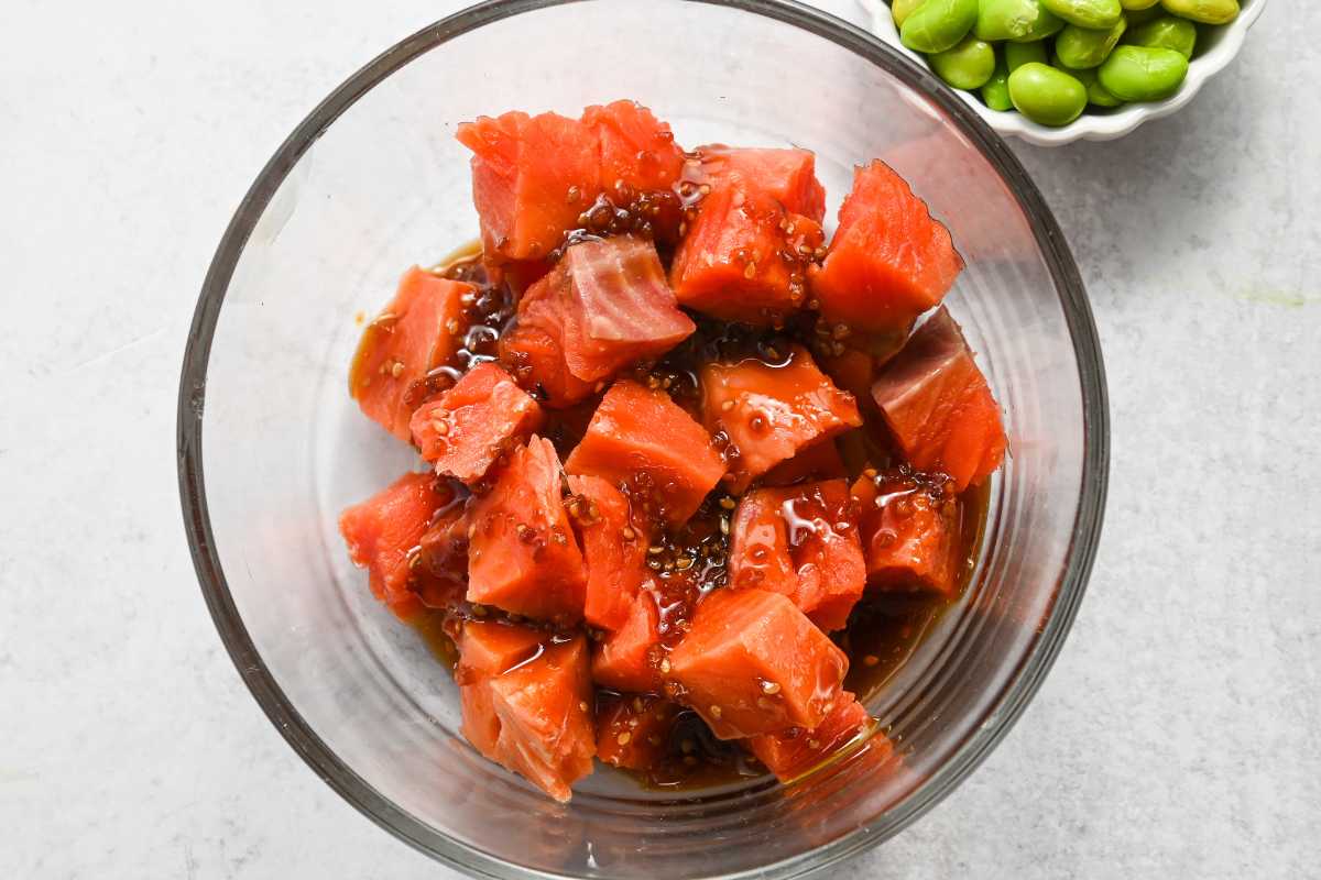 raw salmon cubes marinating in teriyaki sauce in a glass dish.