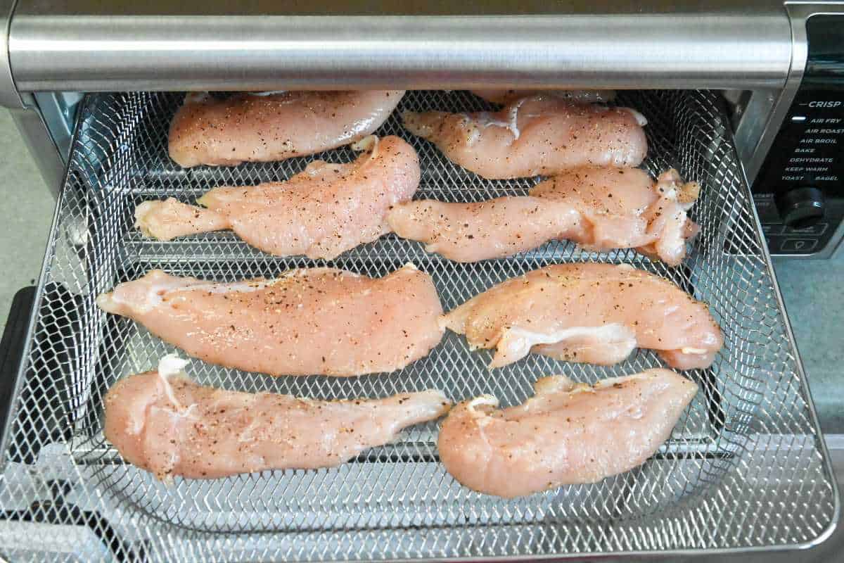 uncooked chicken tenders on an air fryer tray.