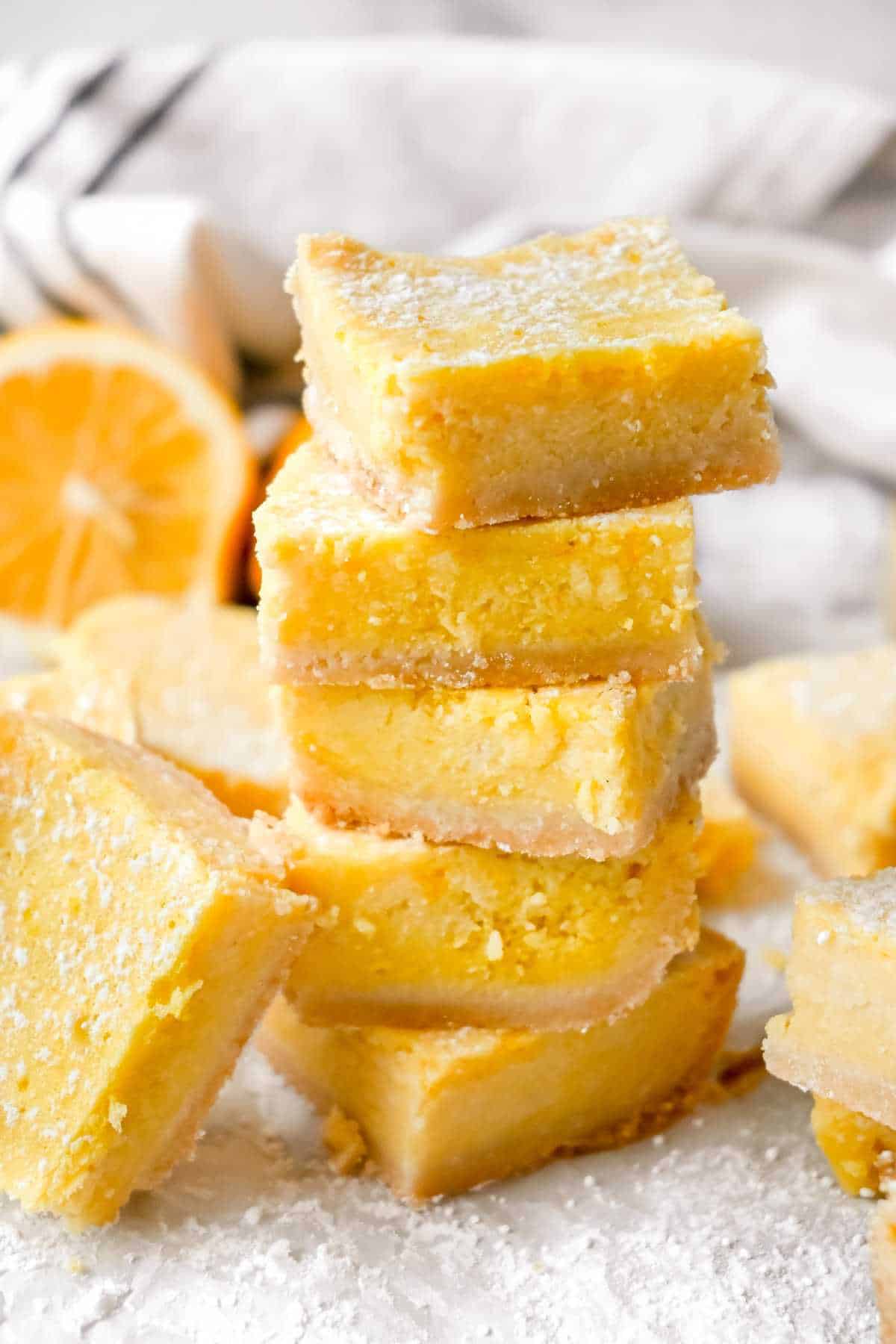 stack of meyer lemon bars with a lemon behind them.